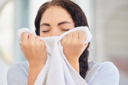 Woman spelling clean bathroom towel